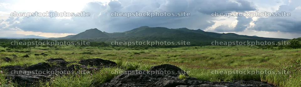 Kumamoto volcanic meadow with dark rocks and green landscape – stock photos 14762x4268