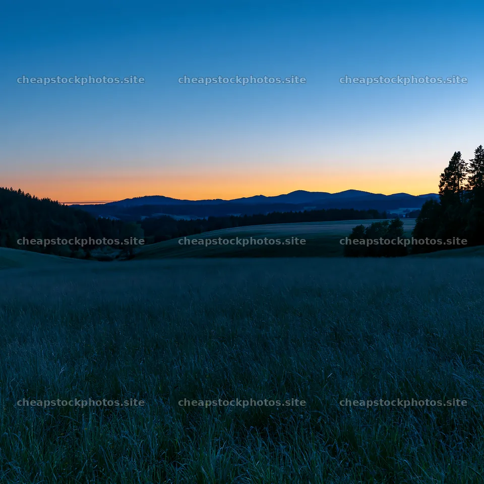 Rolling meadows at dusk with mountains in the background – stock photos 7938x7938