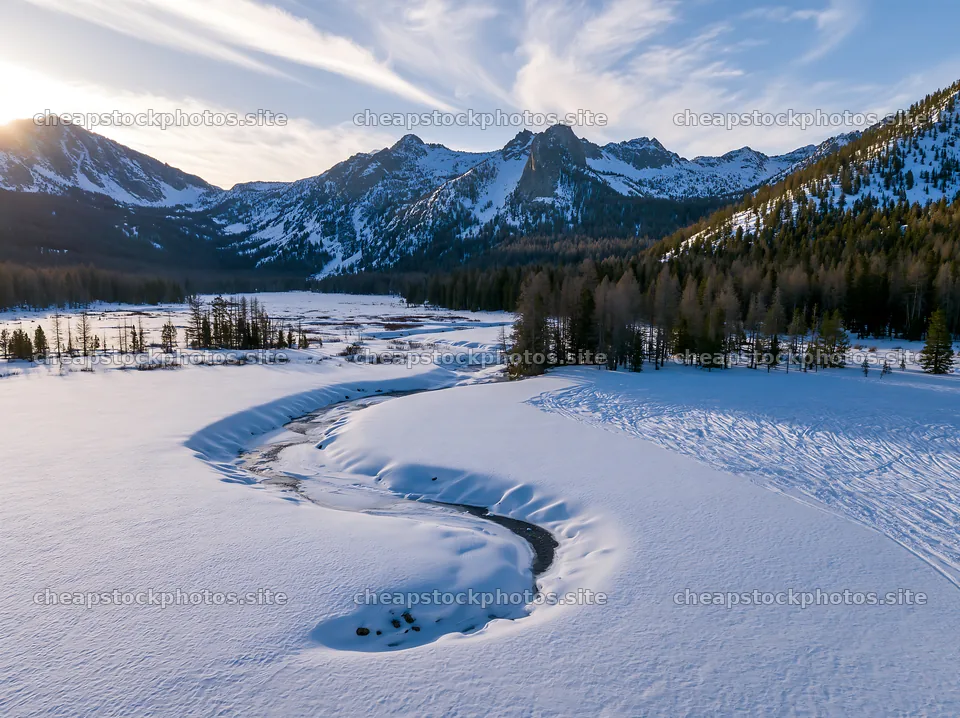 Aerial view of a snowy meadow valley with mountains in the distance – stock photos 9174x6866