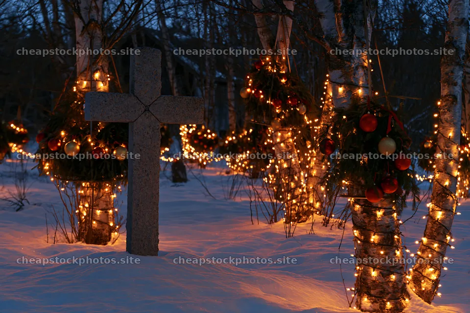 Stone Christian cross in snowy meadow with holiday lights – stock photos 9722x6480