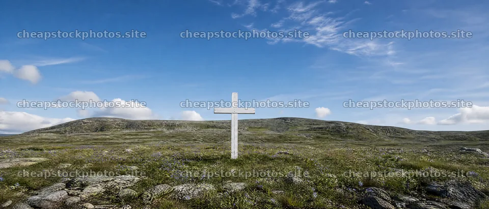 White Christian cross in wildflower meadow under blue sky – stock photos 12124x5196