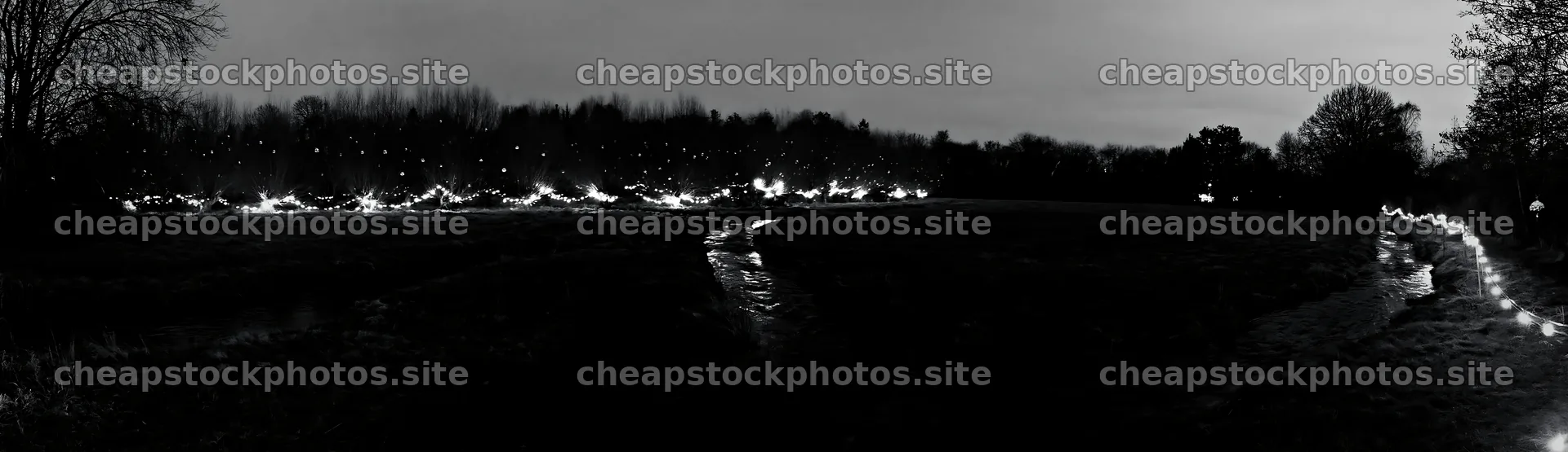 Christmas lights at dusk beside stream in meadow – stock photos 14762x4268