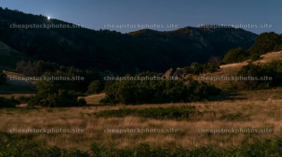 Moonlit meadow with mountains in the background at night – stock photos 10608x5938