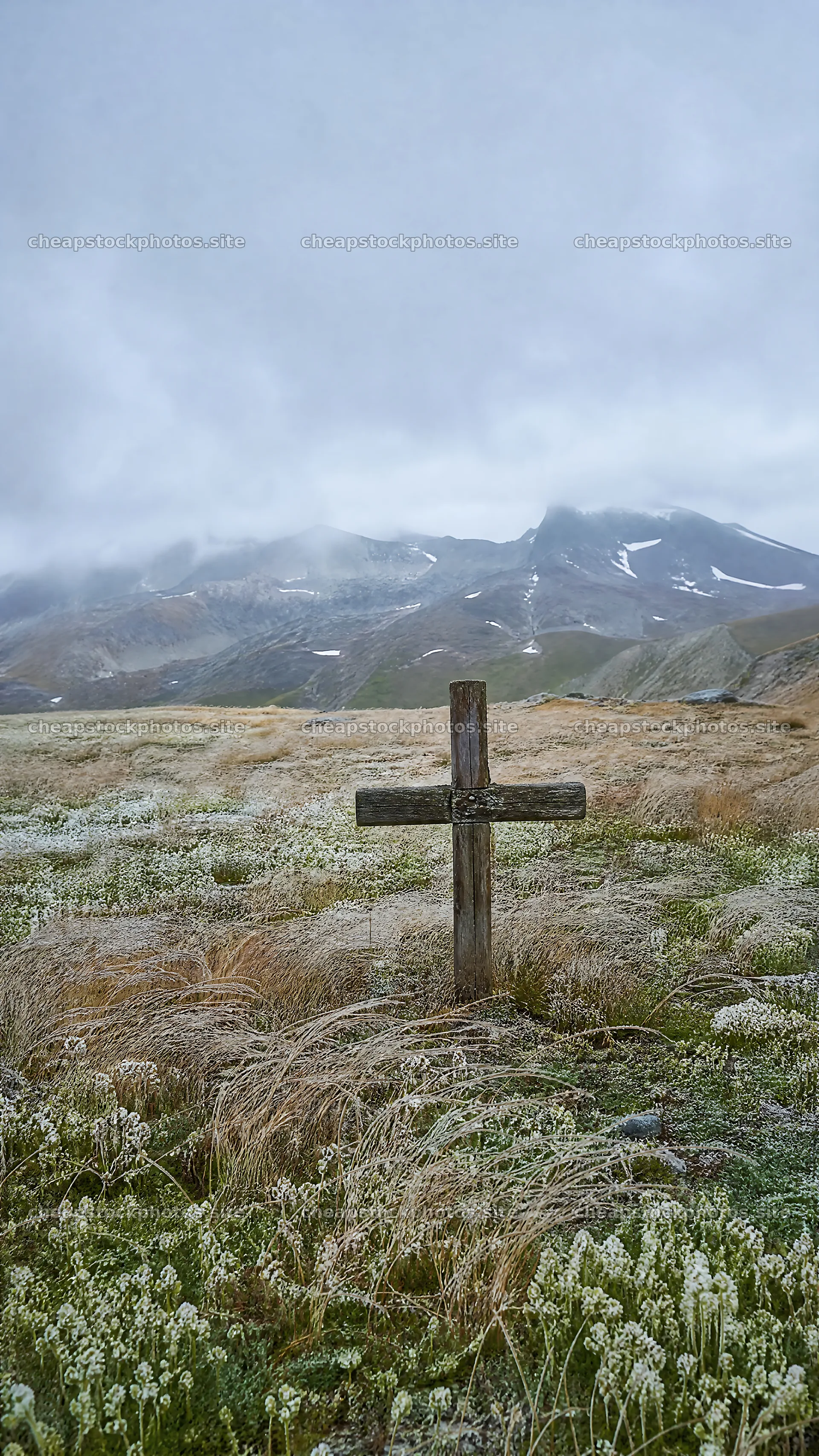 Christian cross in winter mountain meadow with cloudy skies – stock photos 5952x10584