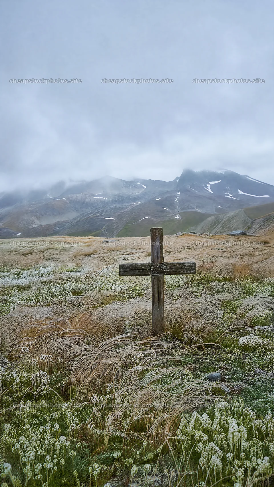 Christian cross in winter mountain meadow with cloudy skies – stock photos 5952x10584