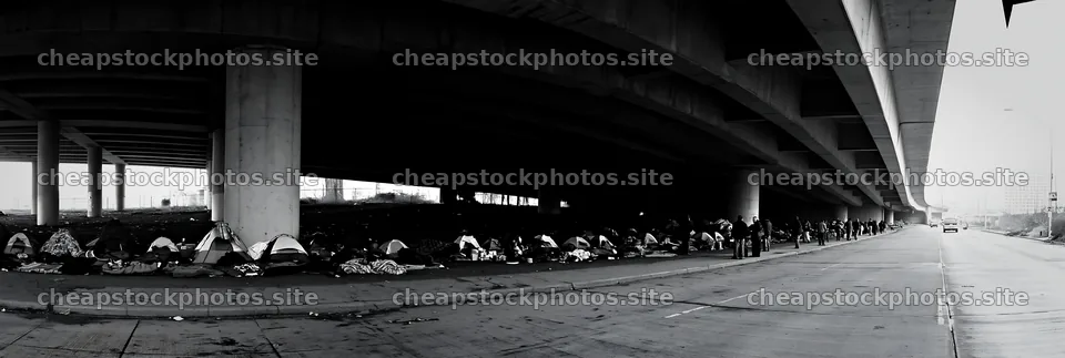 Urban poverty beneath highway infrastructure with tents and people – stock photos 13690x4602