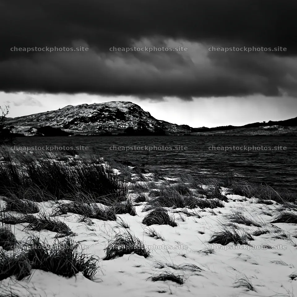 Snowy lakeside meadow with dark clouds in the background – stock photos 7938x7938