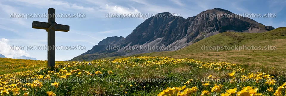 Christian cross in meadow with mountains and flowers – stock photos 13690x4602
