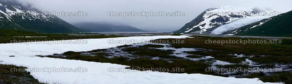 Snowmelt meadow with mountains and cloudy sky in the background – stock photos 14762x4268