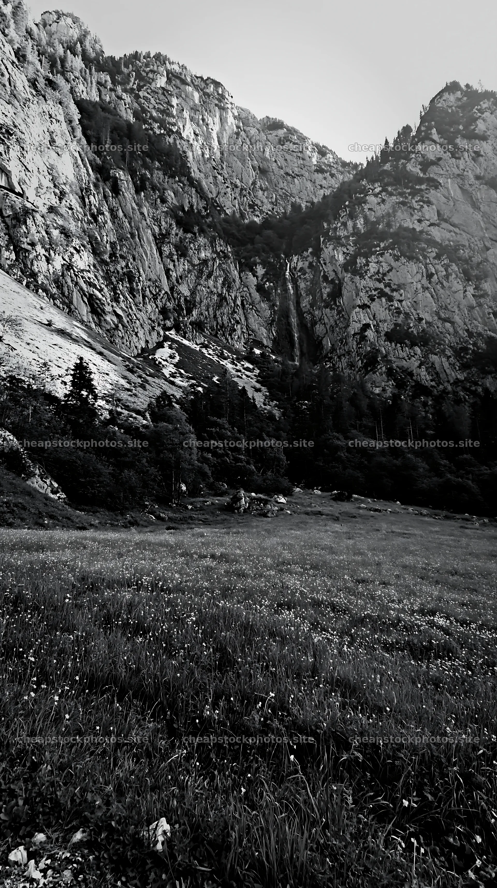 Meadow beneath crags with steep mountains and waterfall – stock photos 5938x10608