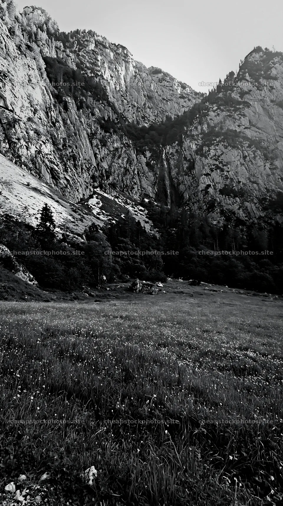 Meadow beneath crags with steep mountains and waterfall – stock photos 5938x10608